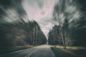 vieux étroit asphalte route avec des arbres sur le côté de le route pendant une voiture balade dans de bonne heure printemps photo