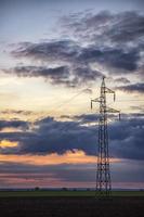 poteaux et aérien Puissance lignes silhouettes dans le crépuscule. électricité génération et distribution. électrique Puissance industrie et la nature concept photo