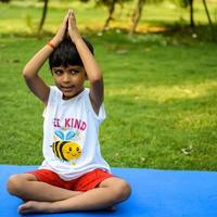 asiatique intelligent enfant Faire yoga pose dans le société parc Extérieur, enfants yoga pose. le peu garçon Faire yoga exercer. photo