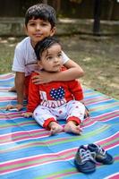 deux content garçons dans société parc, content asiatique frères qui sont souriant Heureusement ensemble. frères jouer en plein air dans été, meilleur amis. bambin bébé garçon en jouant avec le sien content frère dans le jardin photo