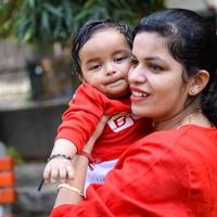 aimant maman porter de sa bébé à société parc. brillant portrait de content maman en portant enfant dans sa mains. mère étreindre sa peu 9 mois vieux fils. photo