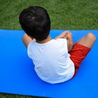 asiatique intelligent enfant Faire yoga pose dans le société parc Extérieur, enfants yoga pose. le peu garçon Faire yoga exercer. photo