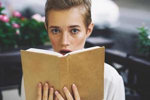 étudiant avec une livre dans le sien mains en train de lire marcher dans le Frais air éducation photo