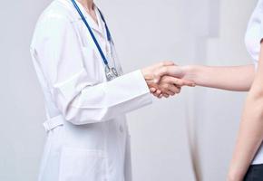 médecin et patient secouer mains avec chaque autre sur une lumière Contexte tondu vue photo