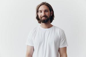 portrait de une homme avec une noir épais barbe et longue cheveux dans une blanc T-shirt sur une blanc isolé Contexte photo