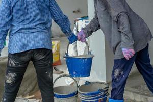 mise au point sélective sur les mains des travailleurs livrent le seau avec du ciment mélangé les uns aux autres sur le chantier de construction. fête du travail et concept de travail d'équipe photo