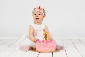 de bonne humeur peu fille avec une de fête gâteau. magnifique fille un année vieux. photo