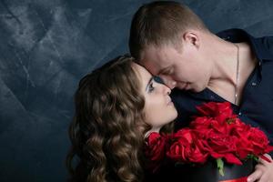 magnifique Jeune couple .câlins, baisers et jouit dépenses temps ensemble, célébrer valentines journée avec rouge des roses. photo