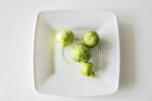 petit vert Bruxelles choux sur une blanc assiette sur une blanc isolé Contexte photo