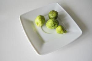 petit vert Bruxelles choux sur une blanc assiette sur une blanc isolé Contexte photo