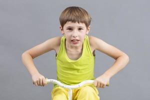 enfant sur une vélo sur une gris Contexte. marrant peu garçon pièces une motard. photo