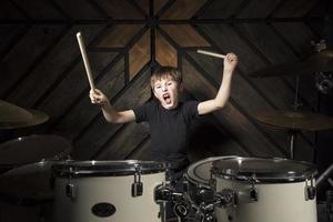 le enfant pièces le tambours. garçon musicien derrière une tambour trousse. photo