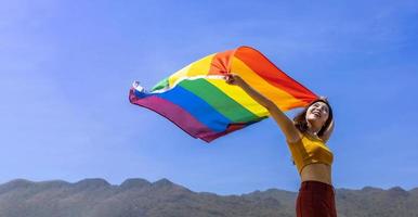 femme en portant coloré arc en ciel drapeau est dansant dans homosexuel parade pour lgbtq fierté mois et à venir en dehors de le placard concept pour le sexe fluide et sexuel égalité liberté photo