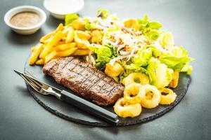 Steak de viande de bœuf grillé avec frites rondelle d'oignon avec sauce et légumes frais