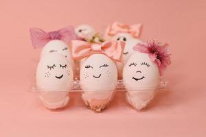 des œufs avec visage et fleurs sur le rose arc, pour Pâques Contexte photo