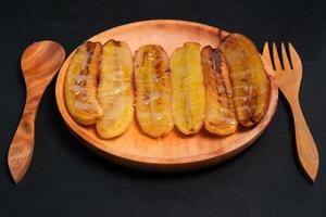 frit bananes avec fondu Lait sur une en bois plaque. populaire rue nourriture dans sud-est Asie, surtout dans Indonésie photo