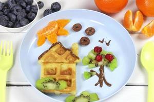 enfants petit déjeuner gaufres et des fruits sur une bleu plaque. une Créatif idée pour une amusement des gamins dessert ou petit déjeuner photo