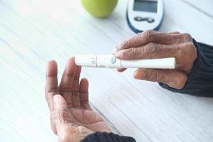 Les femmes âgées diabétiques mesurant le niveau de glucose à la maison photo
