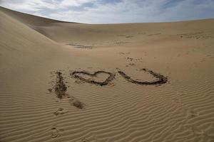 cœur symbole de l'amour arrangé de gris pierre sur d'or le sable sur une d'or dune photo