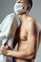 musclé homme avec nu torse médical masque les serviettes dans mains fermer photo