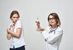 effrayé patient et infirmière avec une seringue dans main sur une lumière Contexte photo