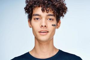 aux cheveux bouclés gars dans une noir T-shirt produits de beauté sur le visage nettoyer peau photo