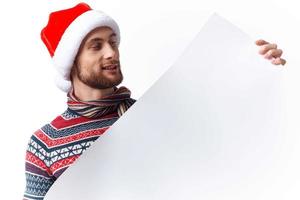 Beau homme dans une Noël chapeau avec blanc maquette affiche Noël copie-espace studio photo