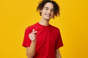 charmant marrant caucasien Jeune homme dans rouge T-shirt spectacle cœur forme geste posant isolé sur plus de Jaune studio Contexte. le meilleur offre avec gratuit endroit pour publicité. émotions pour tous les jours concept photo