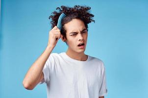 indigné gars ratissage cheveux avec bleu peigne sur isolé Contexte tondu vue photo