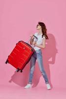 femme touristique avec rouge valise portant des lunettes de soleil amusement rose Contexte photo