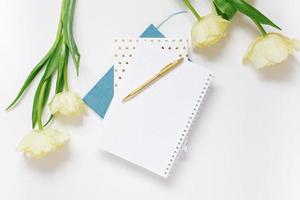 de fête printemps composition Jaune tulipes, une carnet avec une stylo, sur une blanc Contexte. le concept de printemps vacances de une pigiste ou blogueur photo