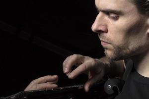 une homme pièces le guitare. visage de une homme avec une musical instrument sur une foncé Contexte. photo