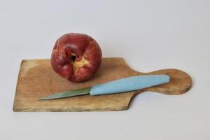 rouge jambu bol ou Jamaïque goyave suivant à une bleu couteau sur une Coupe planche contre une blanc Contexte photo