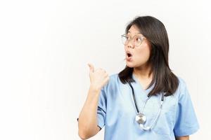 montrant et montrer du doigt produit avec pouce de asiatique Jeune médecin isolé sur blanc Contexte photo