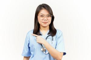 montrant produit et montrer du doigt côté de asiatique Jeune médecin isolé sur blanc Contexte photo