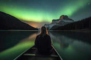 voyageur femme séance sur canoë avec aurore borealis plus de esprit île dans maligne Lac à jaspe nationale parc, alberta, Canada photo