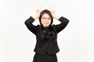 montrant paix signe de magnifique asiatique femme portant noir blazer isolé sur blanc Contexte photo