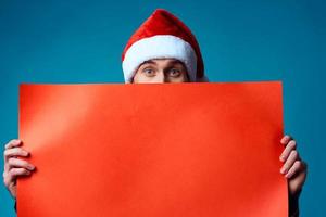 émotif homme dans une Père Noël chapeau en portant une bannière vacances bleu Contexte photo