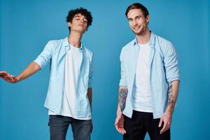 deux copains dans un déboutonné chemise et dans blanc t-shirts sur une bleu Contexte faire des gestes avec mains tondu vue fête photo