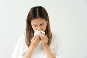 pollen allergiques, asiatique Jeune femme éternuements dans une mouchoir ou soufflant dans une essuyer, allergique à sauvage printemps fleurs ou fleurs pendant printemps. allergique réaction, respiratoire système problèmes photo