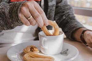 fermer de une homme en mangeant une typique Espagnol petit déjeuner et Churros avec Chocolat photo