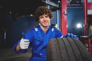 portrait une entretien technicien inspecter pneus dans le garage et changement alliage pneus dans le garage. voiture entretien. voiture réparation et entretien concept photo