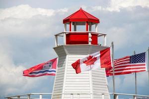 canadien et américain drapeaux sur une rouge et blanc phare photo