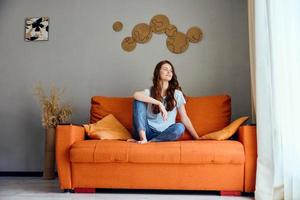 de bonne humeur femme relaxant à Accueil dans le pièce sur le canapé intérieur appartements photo