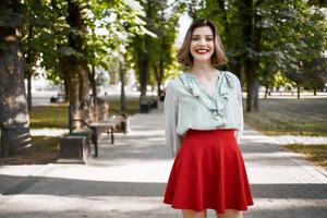 jolie femme en marchant dans le parc dans rouge jupe en plein air photo