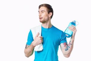 homme dans bleu T-shirt l'eau bouteille faire des exercices santé photo