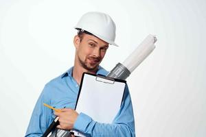 une homme dans une bleu chemise dans une construction casque plans pour construction professionnels photo