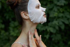 agréable fille émouvant le sien cou avec le sien mains, côté vue cosmétique masque nu épaules photo