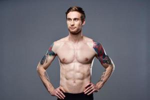 sportif homme tatouages sur le sien bras nu torse bodybuilder gris Contexte photo