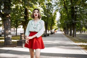 jolie femme en marchant dans le parc dans rouge jupe en plein air photo